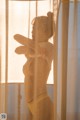 A naked woman standing in front of a window.