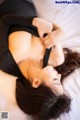 A woman laying on top of a bed in a black dress.