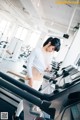 A woman is running on a treadmill in a gym.