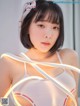 A woman in a white bra top holding a light strip.