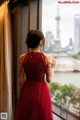 A woman in a red dress looking out a window.