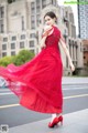 A woman in a red dress is walking down the street.