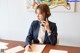 A woman sitting at a desk talking on a cell phone.