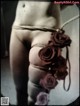 A woman tied up with a rope and roses on her butt.