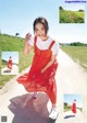 A young girl in a red dress is walking down a dirt road.