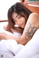 A woman laying in bed with a tattoo on her arm.