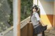 A woman in a school uniform leaning against a wall.