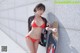 A woman in a red bikini holding a skateboard.