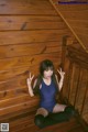 A woman in a blue bodysuit sitting on a wooden staircase.