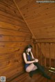 A woman sitting on a wooden deck in a blue dress.