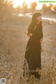 A woman in a black dress standing in a field.