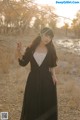 A woman in a black dress standing in a field.