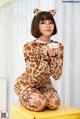 A woman in a leopard print pajamas sitting on a yellow box.