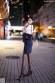 A woman in a skirt and heels standing on a city street.