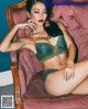 A woman in a green lingerie sitting on a pink chair.