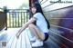 A woman sitting on a wooden deck with her legs crossed.