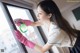 A woman in pink gloves cleaning a window with a spray bottle.