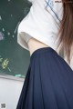 A woman in a white shirt and blue skirt standing in front of a blackboard.