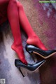 A woman in red tights and black high heels sitting on a rug.