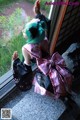 A woman with green hair sitting on a window sill.