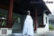 A woman in a white dress standing in front of a building.