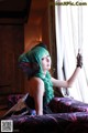 A woman with green hair sitting on a couch.