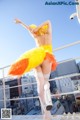 A woman in a yellow and orange dress is dancing on a rooftop.