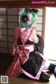 A woman in a pink and black kimono sitting on the floor.