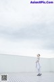 A woman in a white dress standing on a tiled floor.