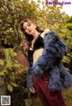 A woman in a blue fur coat posing for a picture.