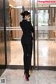 A woman in a black suit standing in front of a glass door.