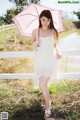 A woman in a white dress holding an umbrella.