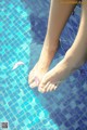 A woman's feet in a swimming pool with pink petals floating in the water.