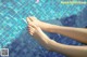 A woman's feet in a swimming pool with pink flowers.