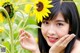 A woman holding a sunflower in front of her face.