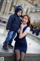 A woman and a child pose for a picture in front of a building.