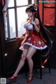 A woman in a red and white dress sitting on a window sill.