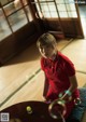 A woman in a red shirt sitting on the floor with soap bubbles.