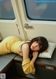 A woman laying on a train seat with her head on a pillow.