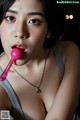 A woman with a pink lollipop in her mouth.