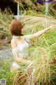 A woman in a white lingerie standing in tall grass.