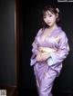 A woman in a purple kimono posing for a picture.