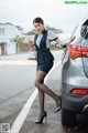 A woman standing next to a car on the side of the road.