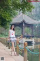 A woman in a white dress standing on a wooden bridge.