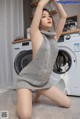 A woman sitting on the floor in front of a washing machine.