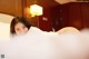 A woman laying on top of a bed covered in white sheets.