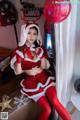 A woman dressed as a santa claus sitting on a window sill.