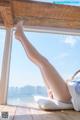 A woman laying on a window sill with her legs up.