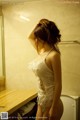 A woman in a white lingerie standing in a bathroom.