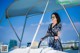 A woman in a black and white dress standing at the helm of a boat.